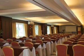 Ein Konferenzraum mit Tischen und Stühlen, Klimaanlagen und einer Projektionsleinwand.