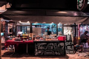 Ein Imbissstand mit einem Schild, auf dem 'DON VITO GRILL' steht, der Meeresfrüchte und gegrilltes Fleisch anbietet.