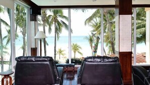 A room with large windows, leather chairs, and a view of the beach. - Mandarin Island Hotel Boracay (Boracay Island)