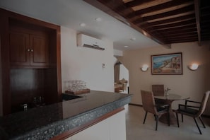 Una cocina con encimera de granito, armarios de madera y una zona de comedor con sillas y mesa.