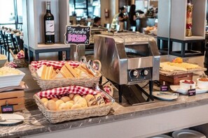 Un buffet de petit-déjeuner comprenant du pain, des viennoiseries et une machine à café.