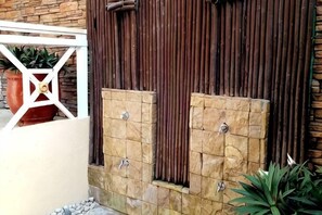 Un muro de ladrillo con una reja de metal, una planta en maceta y una barandilla blanca.
