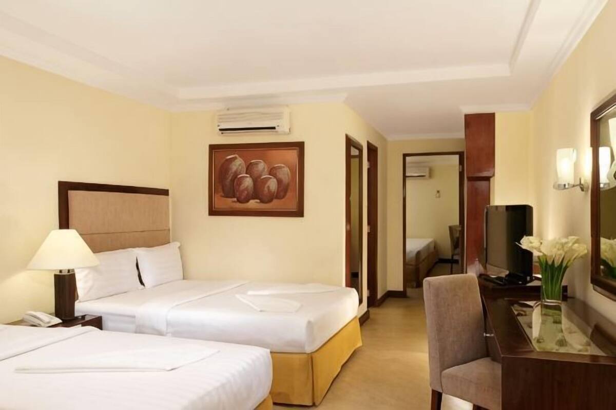 Habitació d'hotel amb dos llits, escriptori, cadira, televisió i un quadre a la paret.