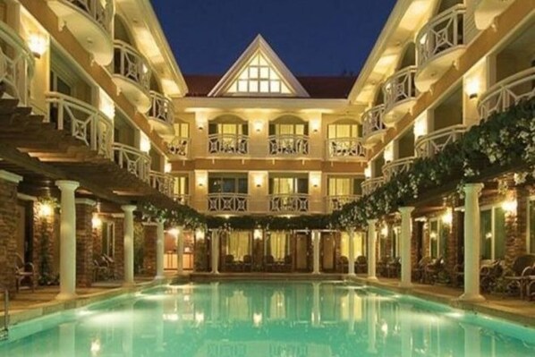Et hotel med en stor swimmingpool, flere altaner og et centralt atrium.