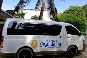 Ein weißer Van mit der Beschriftung 'Boracay Mandarin Island Hotel' steht draußen geparkt.