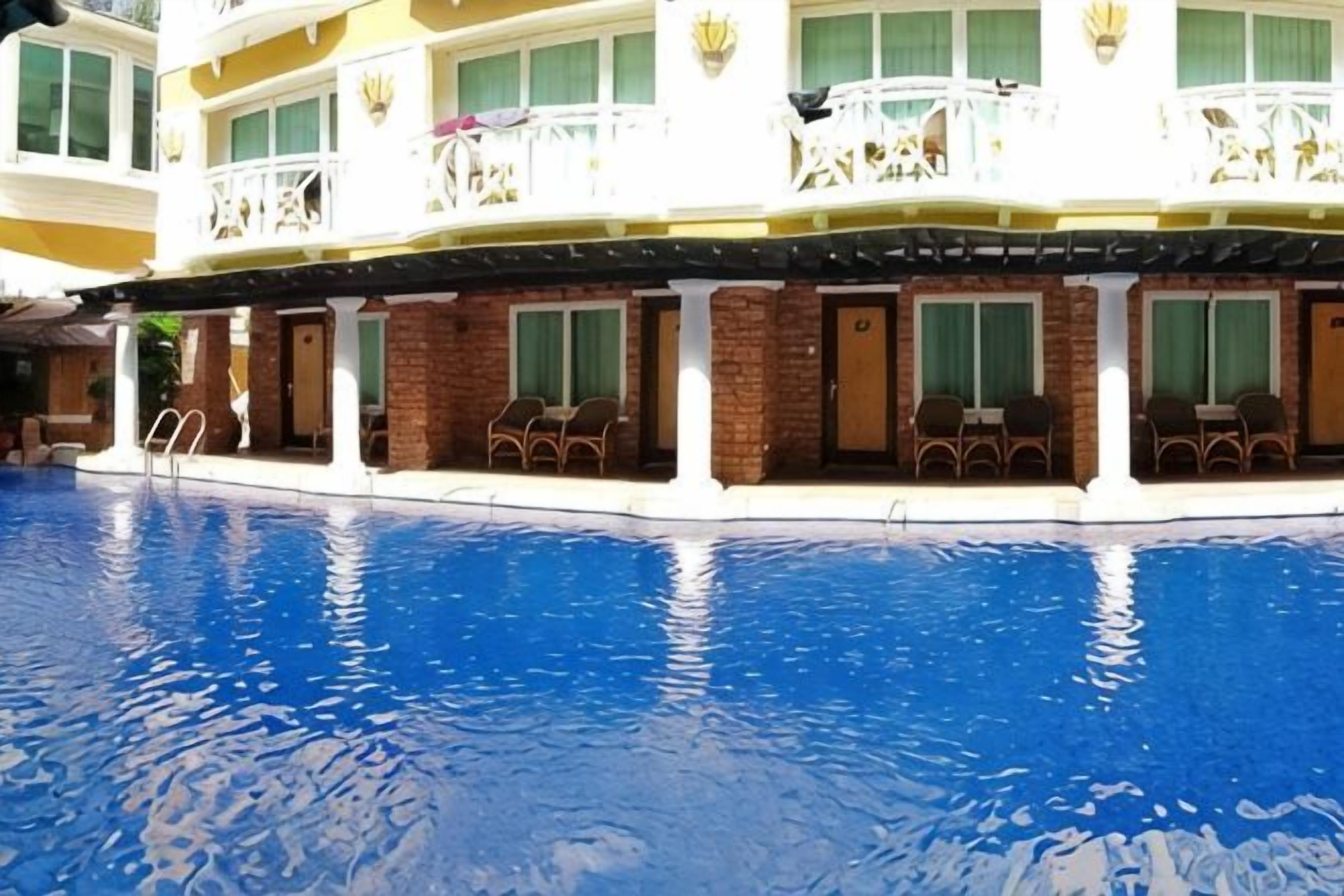 Hotel com piscina, área de estar externa e um edifício com várias andares e varandas.