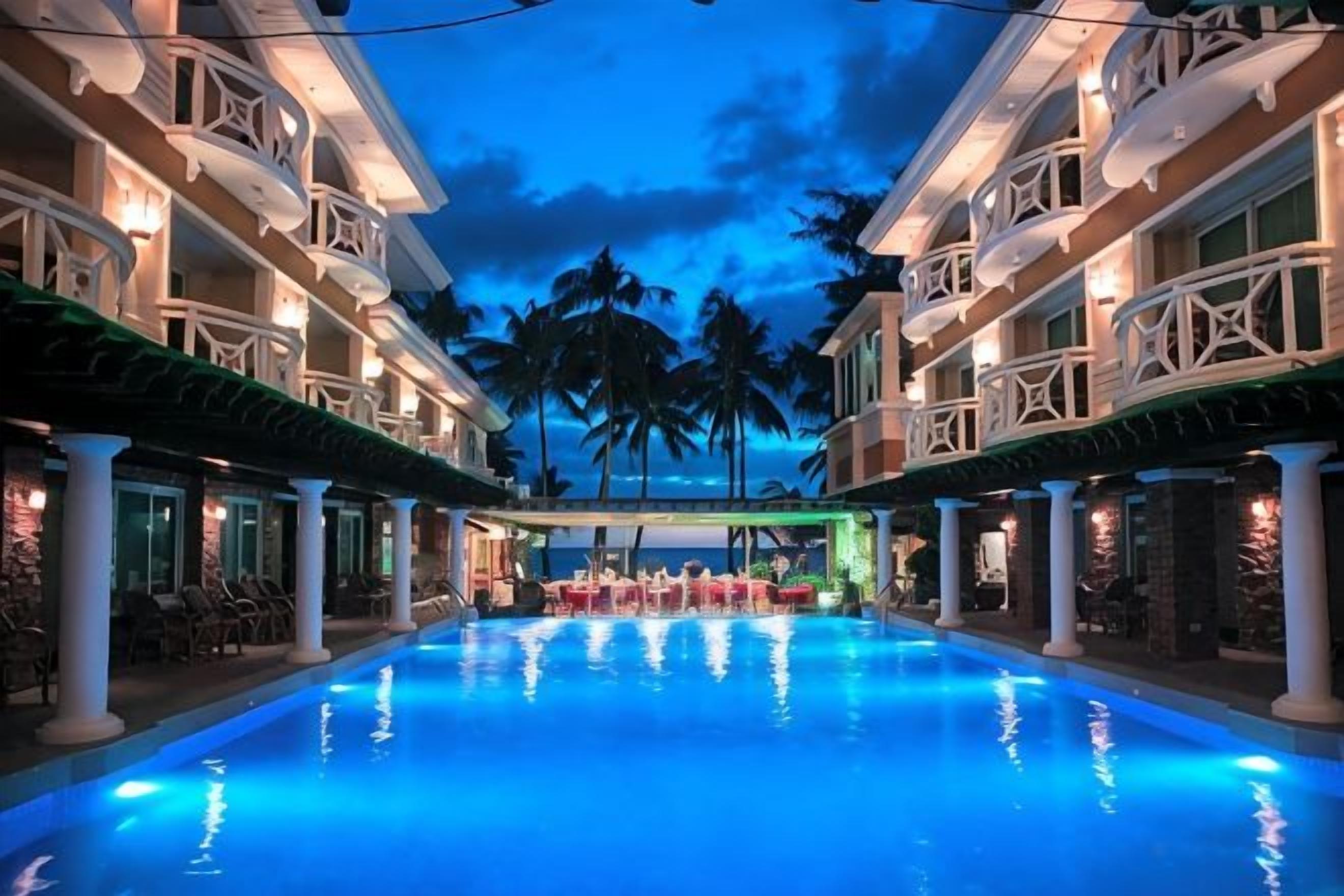 Un espace piscine d’hôtel doté de plusieurs niveaux de balcons et offrant une vue dégagée sur la piscine.