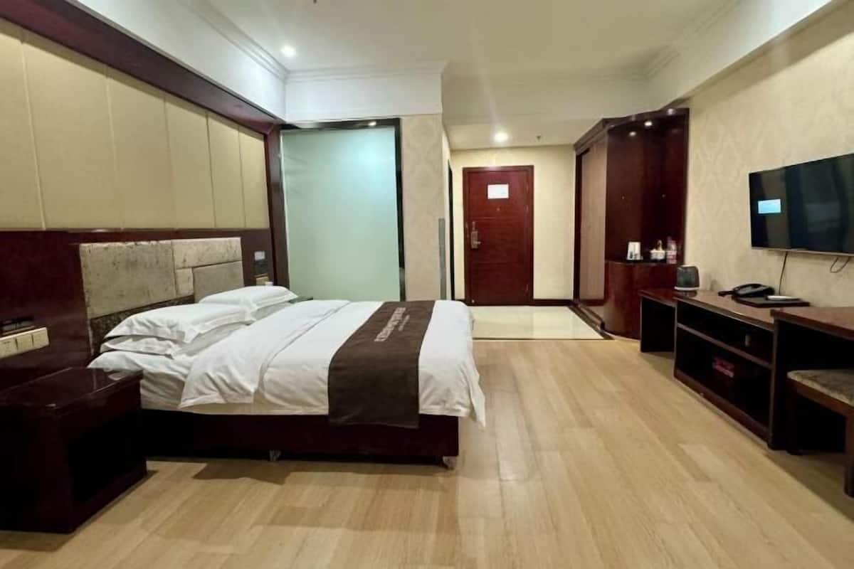 A hotel room with a bed, a desk, a television, and a wardrobe.