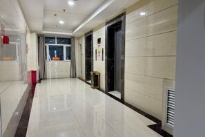 A clean, well-lit hallway with a tiled floor, a trash bin, and a door leading to another room. - Super 8 Hotel (Qitai Tuanjie South Road Branch) (Qitai)