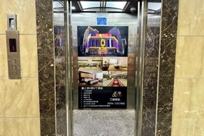 An elevator with a digital display advertising a hotel.