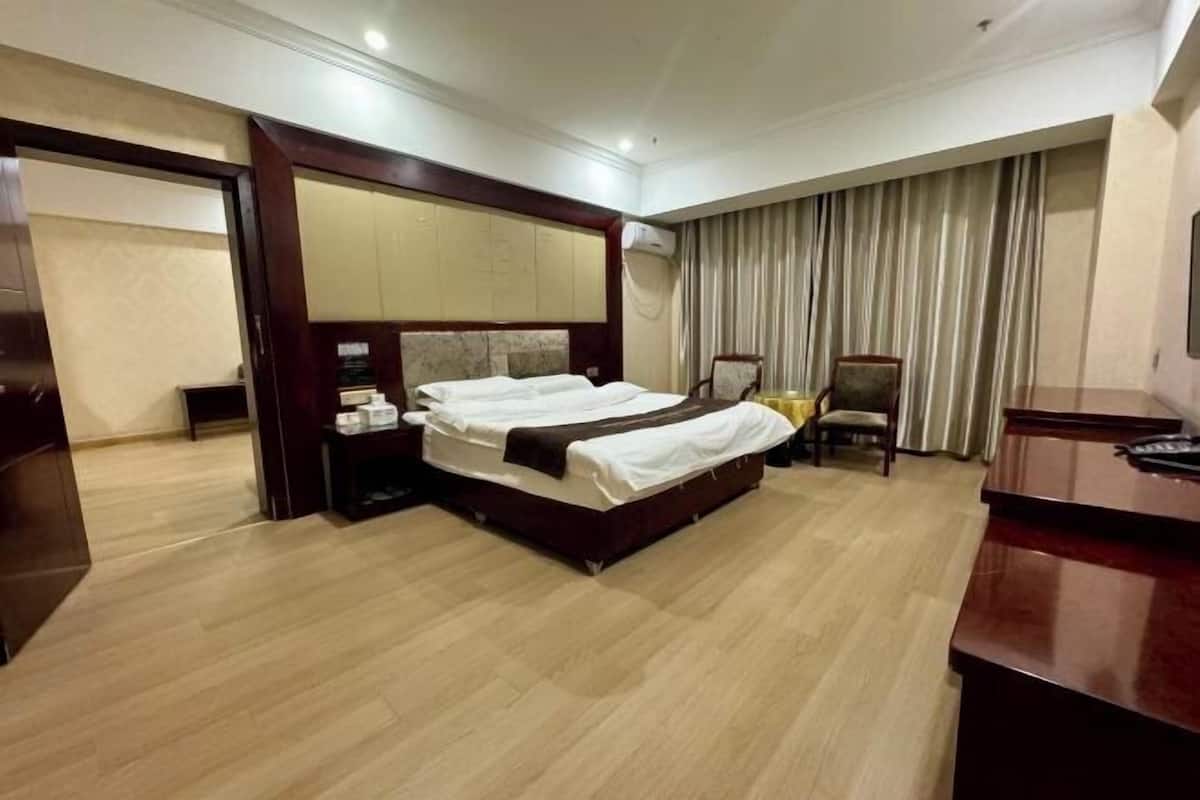 A hotel room with a large bed, a desk, and a chair.