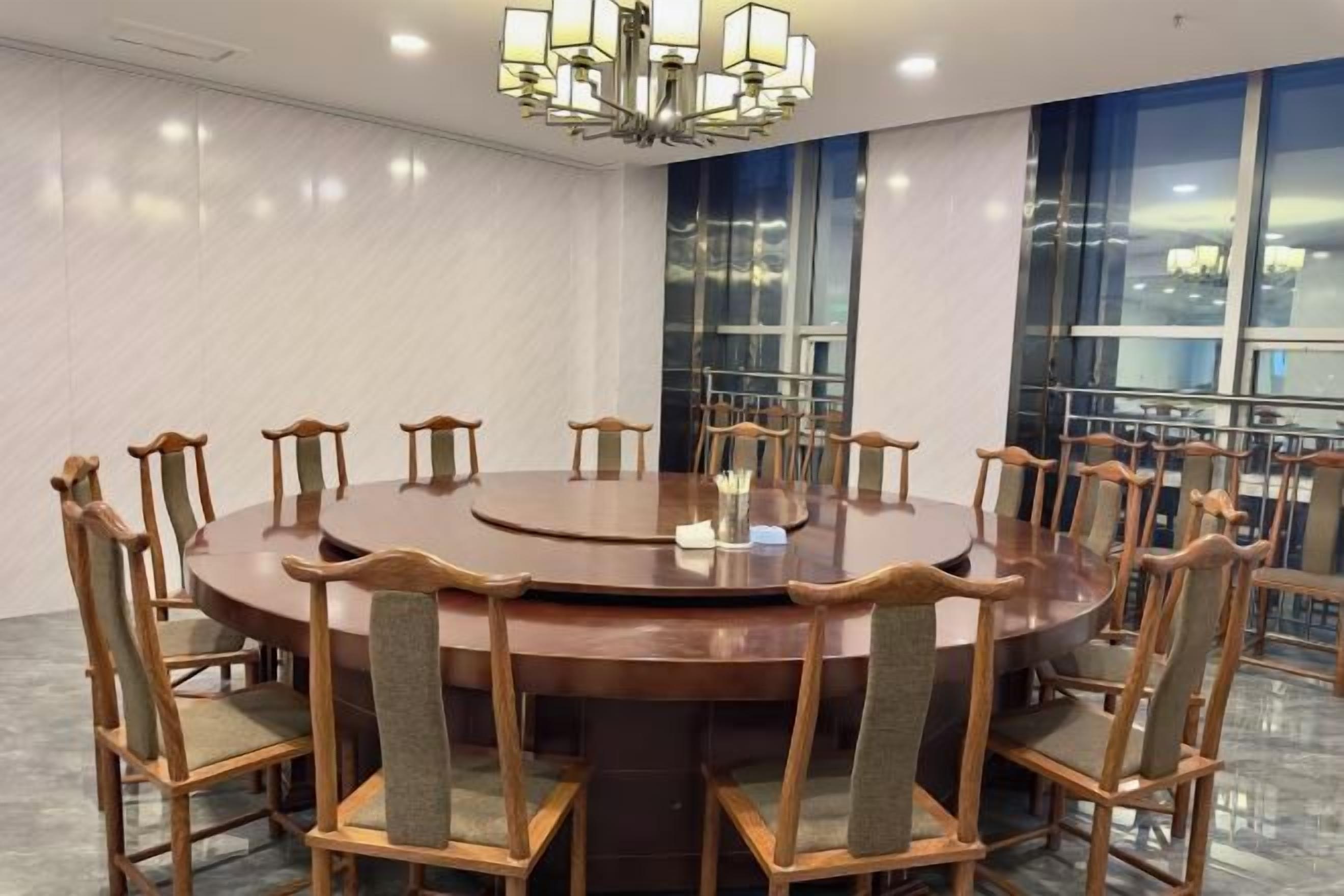 A conference room with a round table, wooden chairs, and a chandelier.
