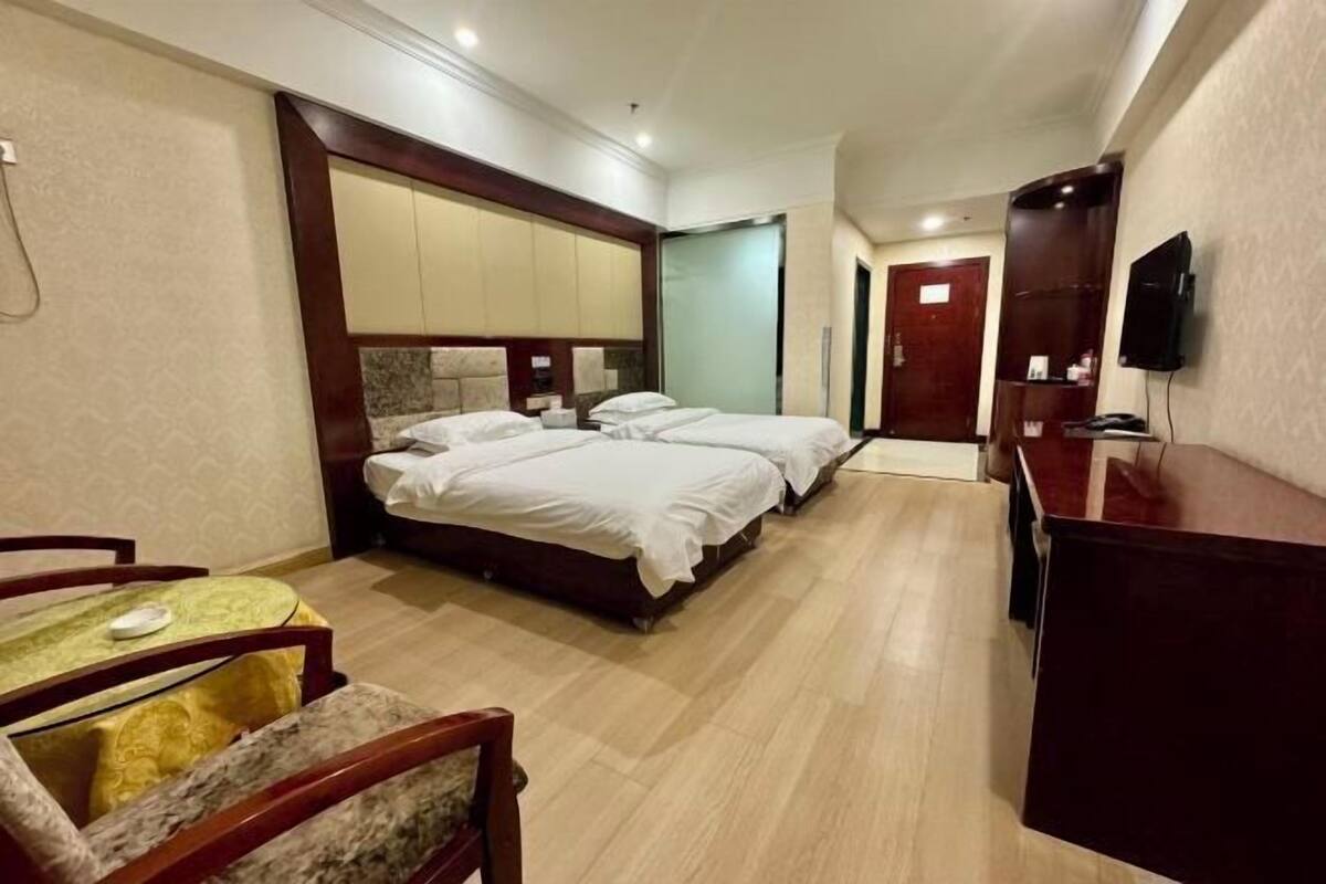 A hotel room with a large bed, a desk, a chair, a television, and a mirror.