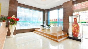 A modern lobby with a reception desk, seating area, and a glass display case. - Boluo Gengxin Hotel (Boluo)