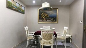 A dining area with a table and four chairs, a painting on the wall, and a ceiling light fixture. - Boluo Gengxin Hotel (Boluo)