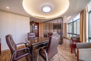 A conference room with a round table, leather chairs, and a decorative wall panel.