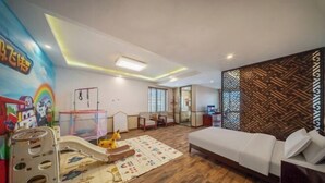 Un salon moderne avec un canapé, un espace de jeux avec des jouets et un mur décoré de motifs.