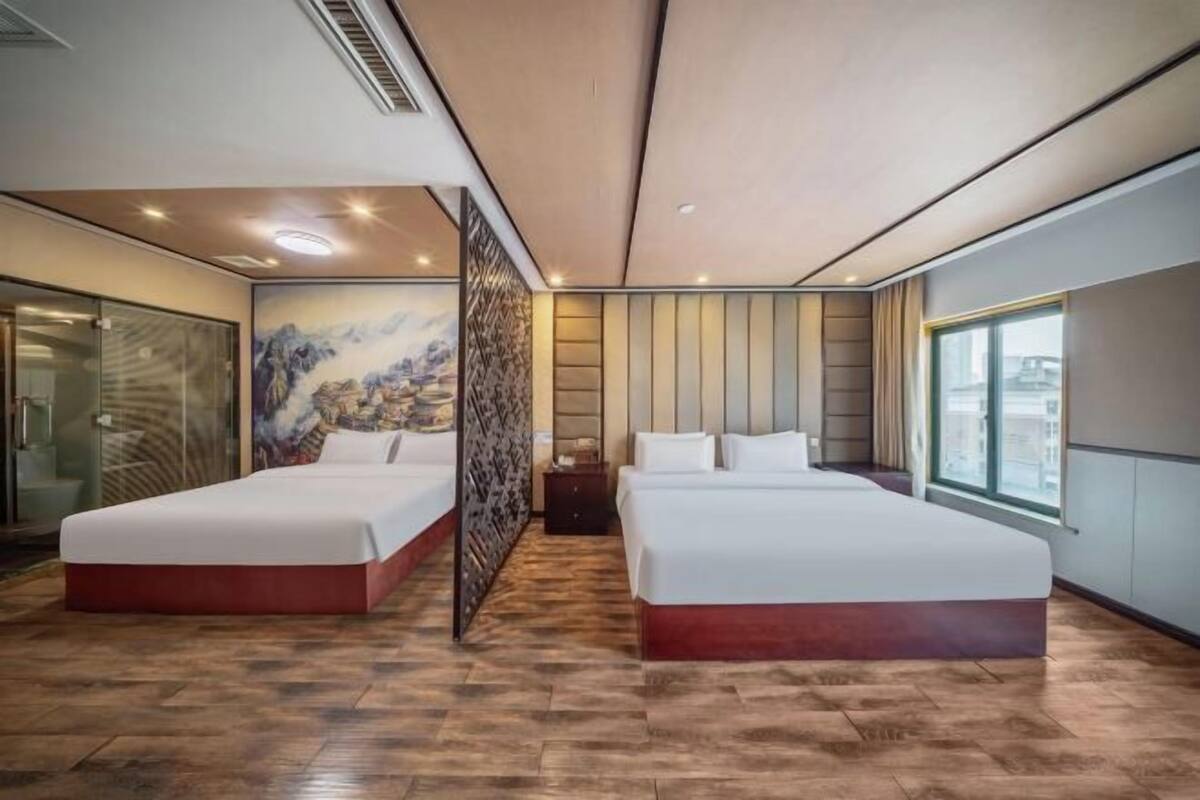 A modern hotel room with two beds, a large window, and a decorative wall mural.