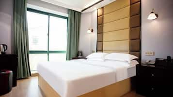 A modern hotel room with a large bed, a bedside table, a nightstand, and a window with curtains.