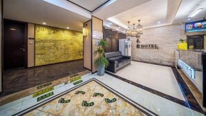 Un hall d’hôtel comprenant un comptoir d’accueil, un espace salon et un mur sur lequel est inscrit le nom de l’hôtel.
