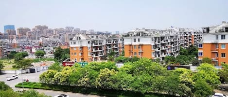 Zona residencial com edifícios de apartamentos e uma rua com veículos, sob um céu claro.