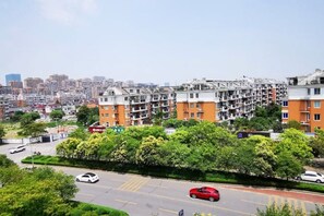 A residential area with multi-story apartment buildings, a road with vehicles, and a clear sky. - Changxing Penglaiju Boutique Hotel (Changxing)