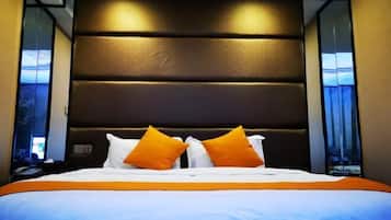 A hotel room with a large bed, a dark headboard, and two windows with curtains.
