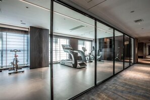 A modern gym with exercise equipment, large windows, and a glass partition wall. - Huaxin Pinyue Hotel (Hai'an)