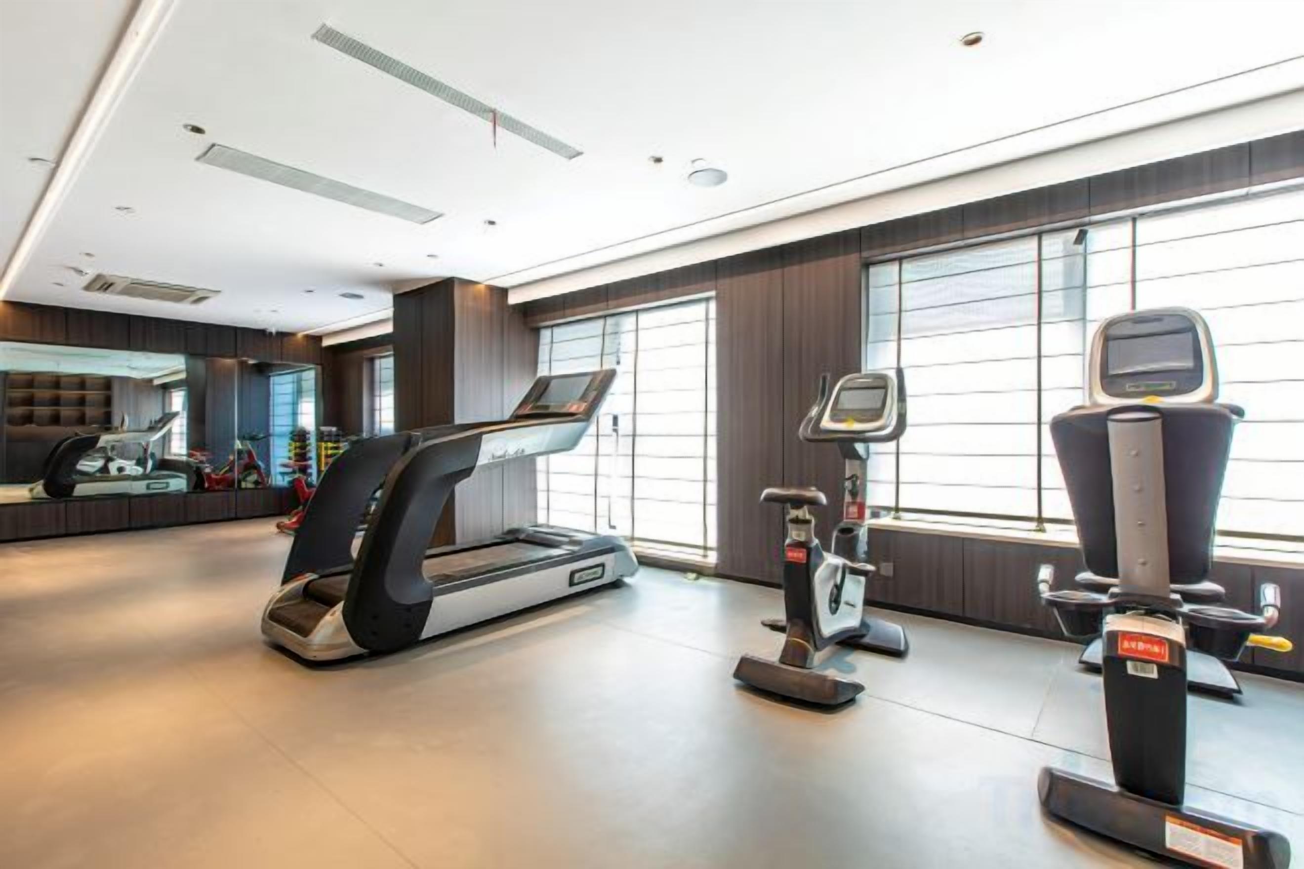 Een moderne sportschool met loopbanden, een hometrainer en een roeimachine.