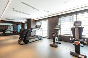 A modern gym with treadmills, a stationary bike, and a rowing machine.