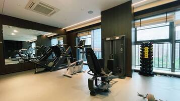 A gym with cardio machines, weightlifting equipment, and a large mirror.