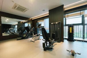 Un gimnasio con máquinas de cardio, equipo de levantamiento de pesas y un espejo grande.