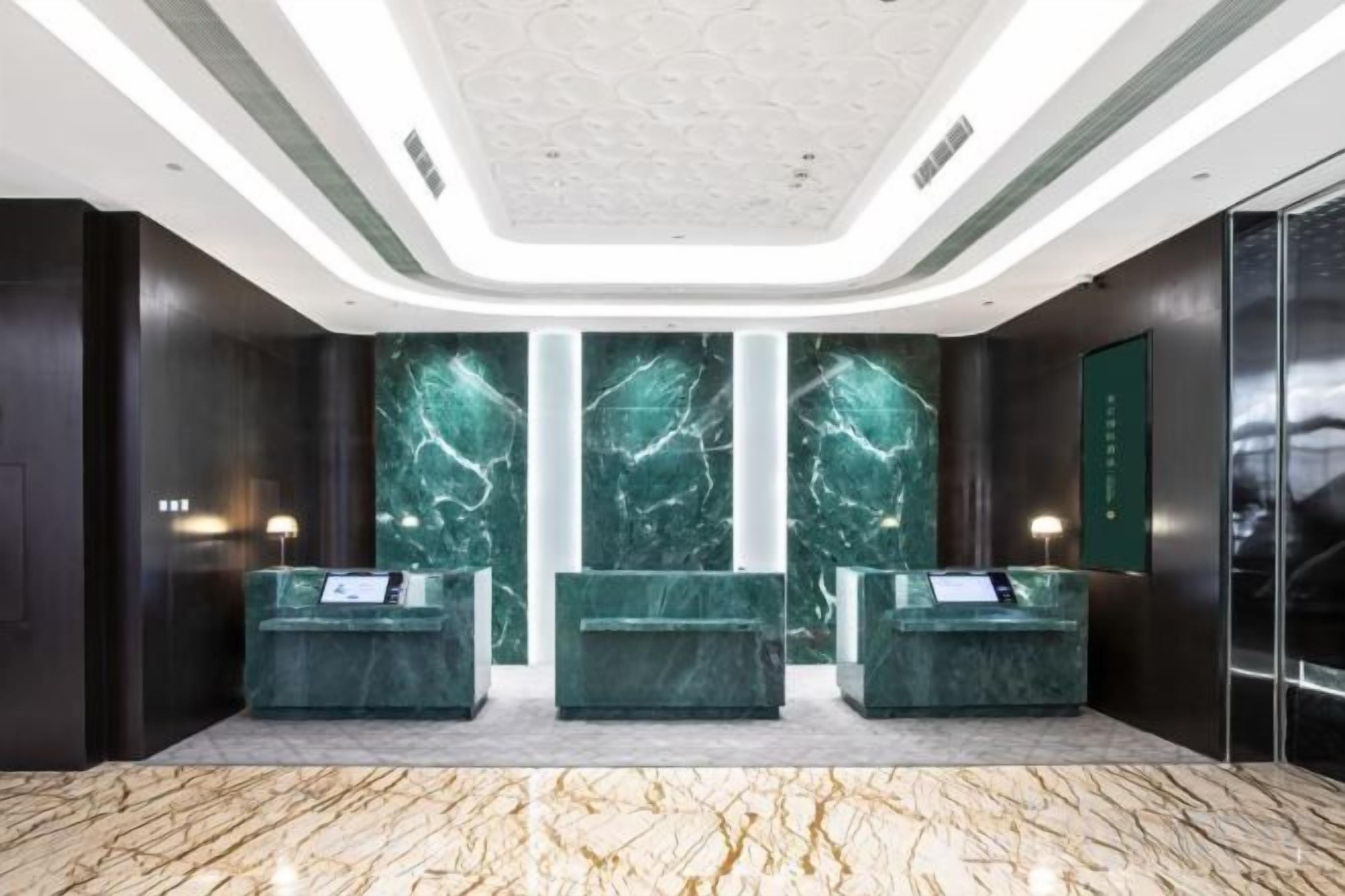 A reception area with marble walls, a reception desk, and a modern ceiling design.
