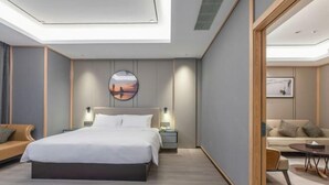 A modern bedroom with a large bed, bedside tables, a sofa, and a dining area.