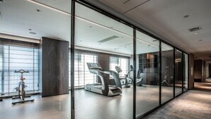 A modern gym with exercise equipment, large windows, and a minimalist design.