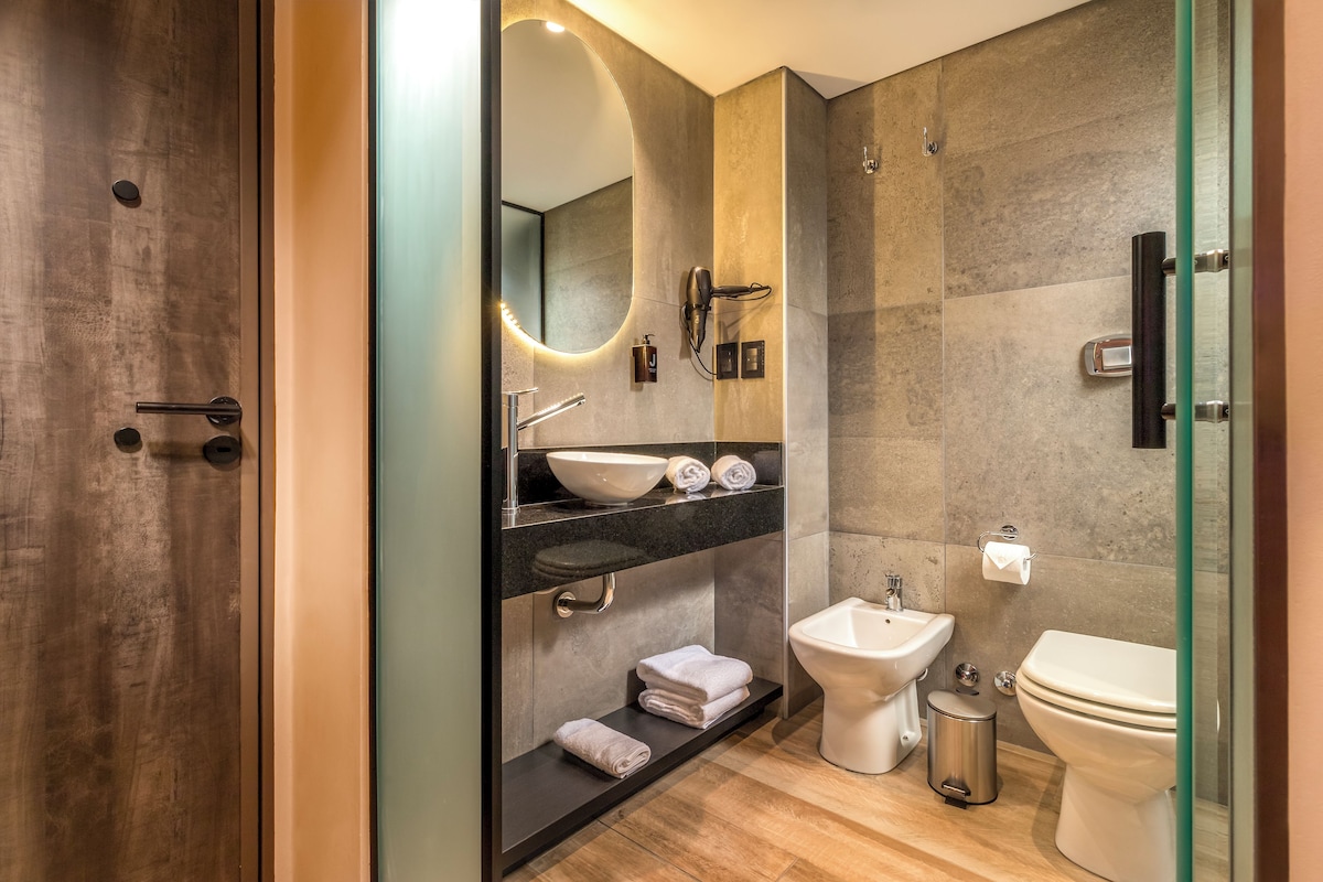 Un baño moderno con un espejo grande, un lavamanos, un bidé y un inodoro.