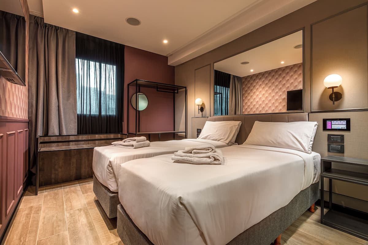 A hotel room with two beds, a large mirror, a TV, and a control panel.