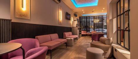 A modern lounge area with sofas, tables, and a ceiling with blue lighting.