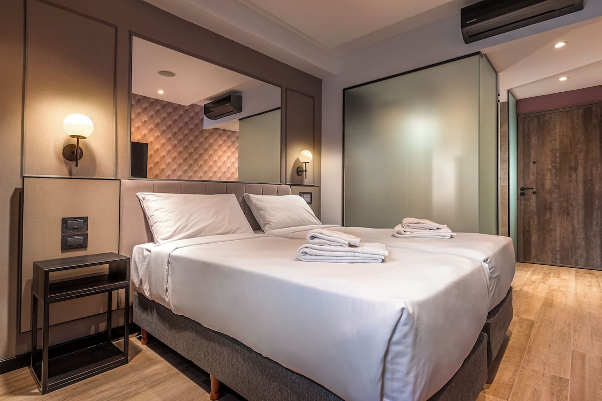 A modern hotel room with a large bed, bedside tables, a mirror, and a wardrobe.