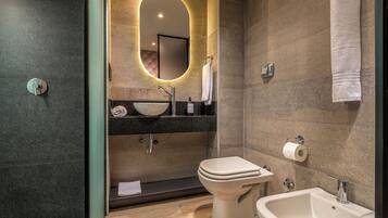 A modern bathroom with a freestanding sink, a toilet, and a bidet.