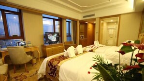 A hotel room with two beds, a desk with a computer, a TV, and a view of the city. - Vienna International Hotel (Meizhou Dingzi Bridge) (Meizhou)