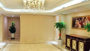 A spacious lobby with a chandelier, potted plants, a painting, and a dark-toned console table. - Vienna International Hotel (Meizhou Dingzi Bridge) (Meizhou)