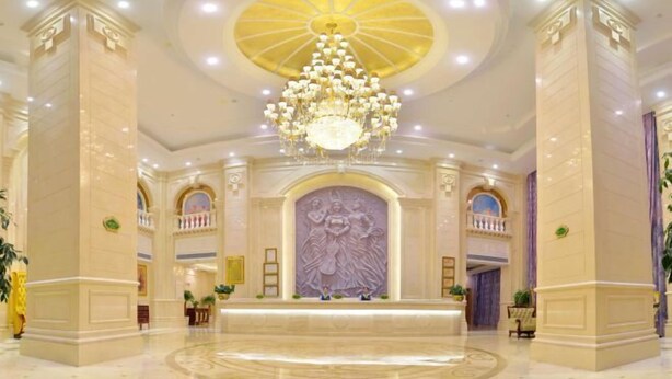 A grand lobby with a large chandelier, marble columns, and a central decorative wall. - Vienna International Hotel (Meizhou Dingzi Bridge) (Meizhou)