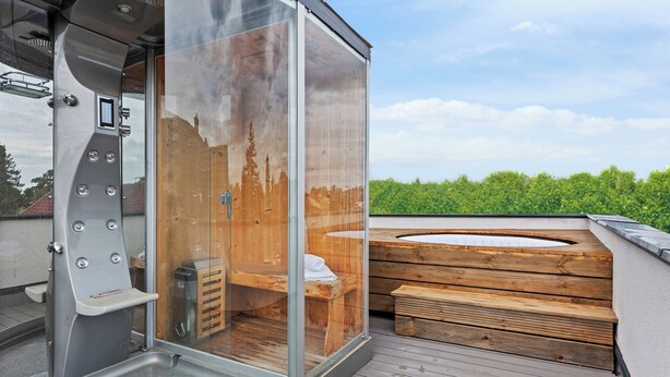 Eine Sauna mit Glaswänden, einer Sitzbank und einem Holzboden.