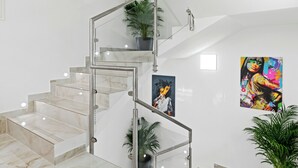 Eine moderne Treppe mit Glastrennwand und Marmorstufen, die zu einer oberen Etage führt.