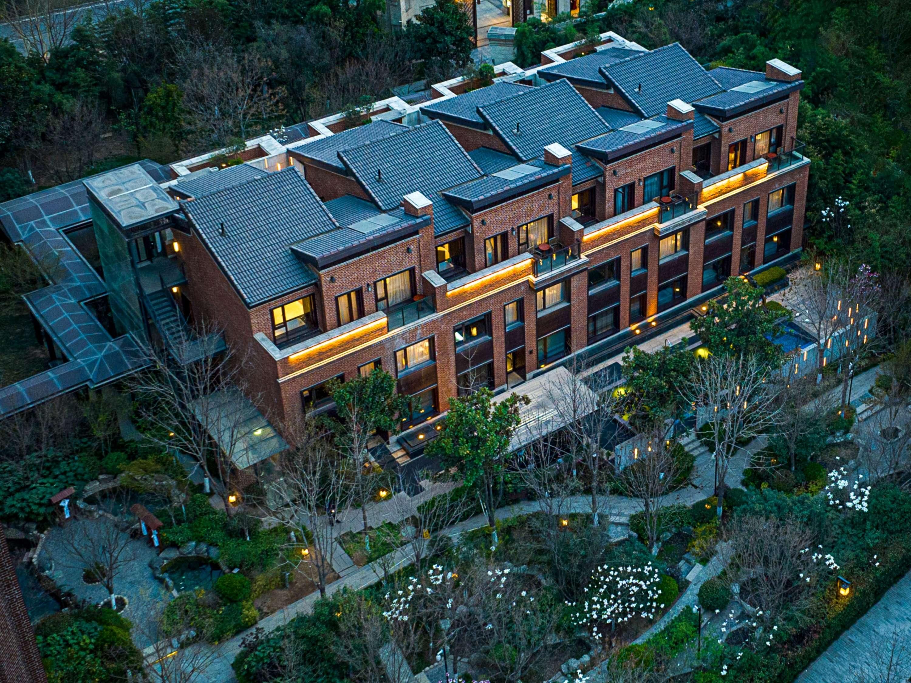 A modern multi-story building with a brick facade, large windows, and a rooftop terrace.