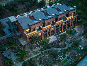 A modern multi-story building with a brick facade, large windows, and a rooftop terrace. - Swissotel Hot Spring Hotel Xi'an Xinxing (Xi'an)