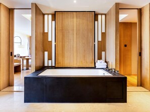 A modern bathroom with a large black bathtub, wooden panels, and a view into a living area. - Swissotel Hot Spring Hotel Xi'an Xinxing (Xi'an)