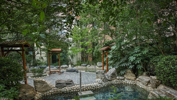 A serene garden with a stone pond, wooden pergolas, and lush greenery. - Swissotel Hot Spring Hotel Xi'an Xinxing (Xi'an)