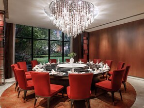 A dining area with a round table set for eight, surrounded by red chairs, under a large chandelier. - Swissotel Hot Spring Hotel Xi'an Xinxing (Xi'an)
